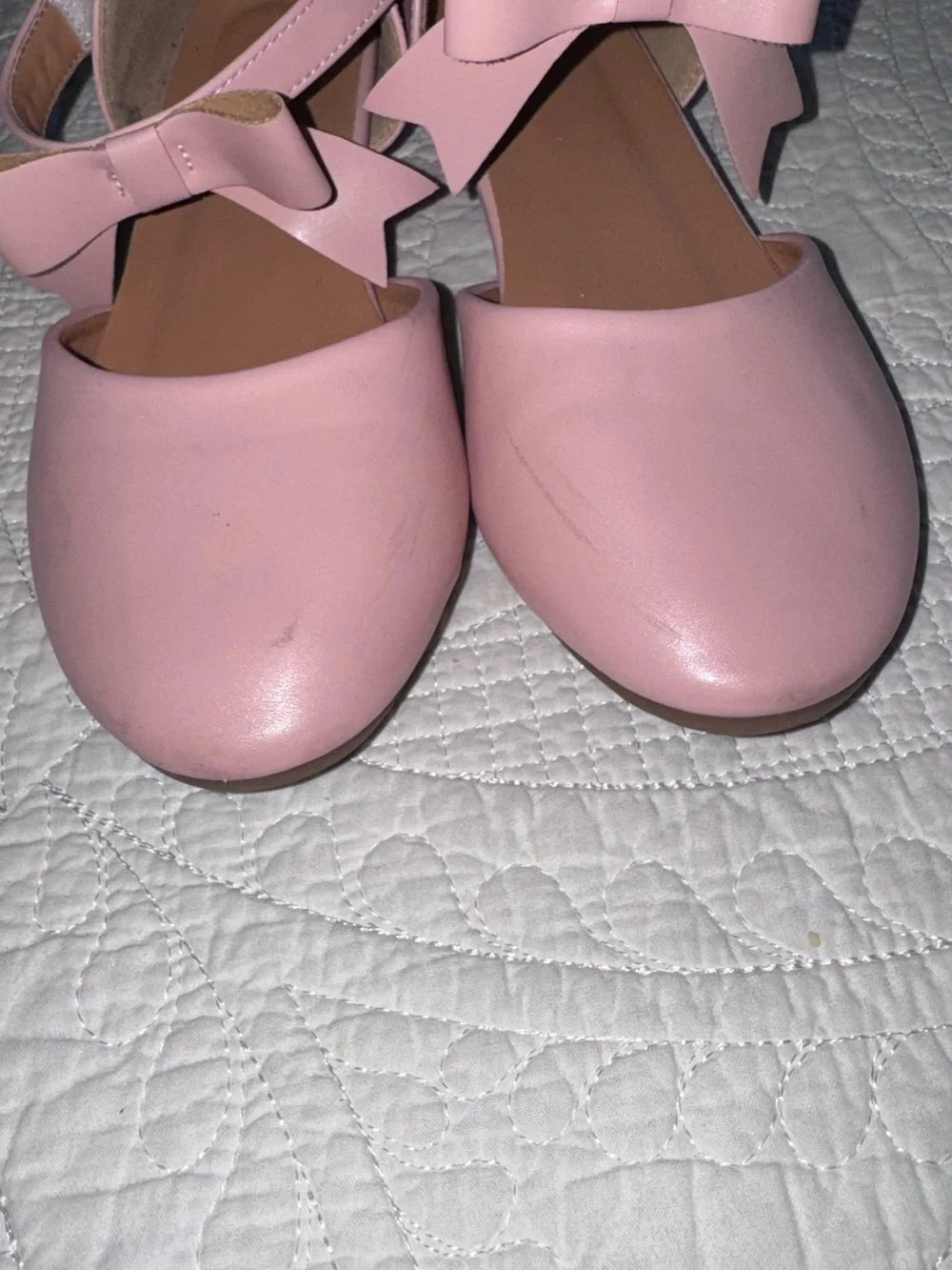 These pastel pink Mary Janes feature a delicate crisscross ankle strap adorned w